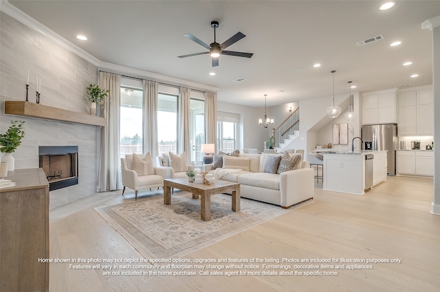4809 Nomad Dr, Midlothian, TX 76065 - living area with light wood-type flooring, a tiled fireplace, ceiling fan, recessed lighting, and stairs