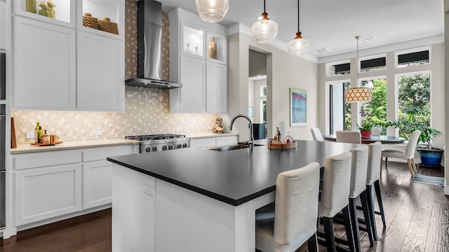 8162 Edgefield Ct, Frisco, TX 75035 - kitchen with wall chimney exhaust hood, dark wood-style flooring, tasteful backsplash, a kitchen island with sink, and crown molding