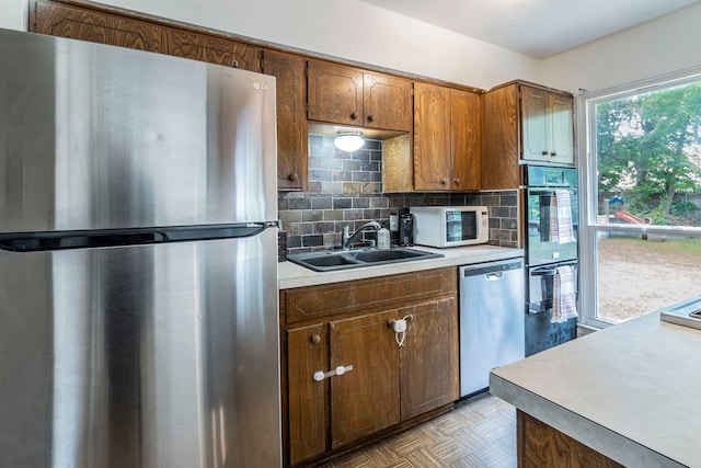 1001 N Ector Dr, Euless, TX 76039 - kitchen with stainless steel appliances, light countertops, a sink, backsplash, and brown cabinetry