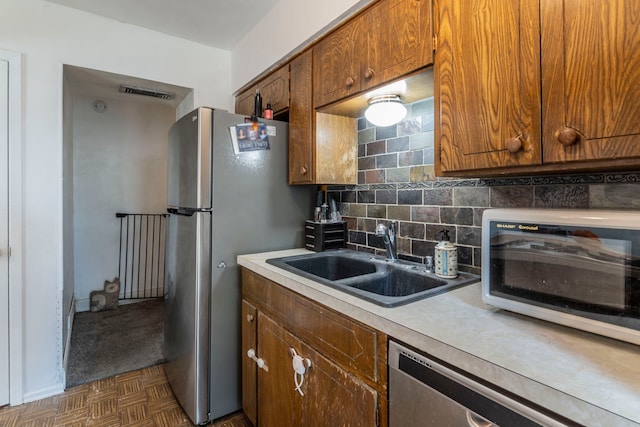 1001 N Ector Dr, Euless, TX 76039 - kitchen featuring appliances with stainless steel finishes, a sink, light countertops, backsplash, and brown cabinets