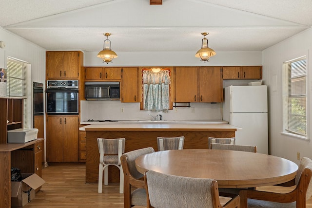 891 Lazy Acres Cir, Pottsboro, TX 75076 - kitchen featuring black appliances, brown cabinetry, light wood-style flooring, light countertops, and pendant lighting