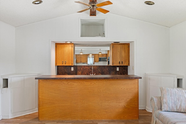 891 Lazy Acres Cir, Pottsboro, TX 75076 - kitchen featuring vaulted ceiling, dark countertops, black microwave, wood finished floors, and ceiling fan