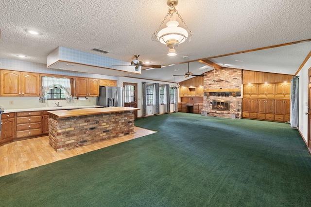 891 Lazy Acres Cir, Pottsboro, TX 75076 - kitchen with stainless steel refrigerator with ice dispenser, a textured ceiling, wood walls, ceiling fan, and a fireplace