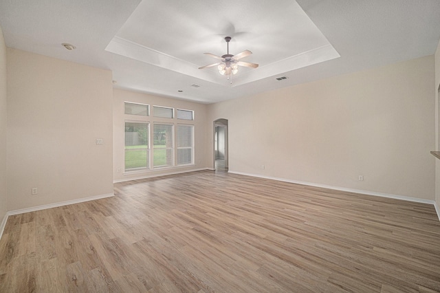 5516 La Bandera Trl, Benbrook, TX 76126 - spare room featuring a raised ceiling, ceiling fan, light wood-style flooring, and arched walkways
