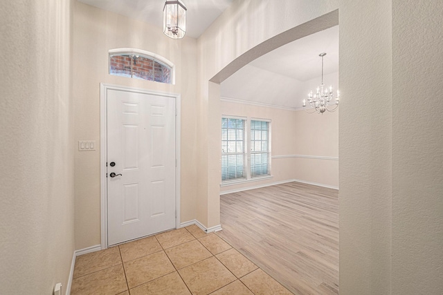 5516 La Bandera Trl, Benbrook, TX 76126 - entrance foyer with a chandelier, light tile patterned floors, baseboards, and arched walkways