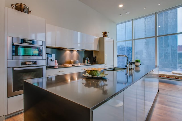 1918 N Olive St Unit 302, Dallas, TX 75201 - kitchen with modern cabinets, a sink, double oven, white cabinetry, and a wall of windows