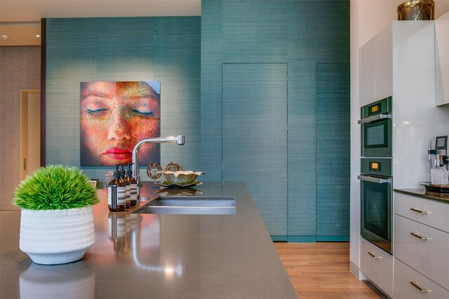 1918 N Olive St Unit 302, Dallas, TX 75201 - kitchen with a sink, white cabinets, light wood-style flooring, modern cabinets, and wallpapered walls
