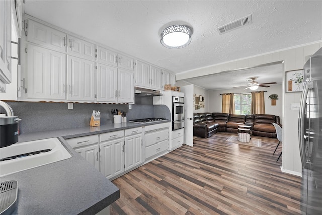 102 Creek Dr, Whitney, TX 76692 - kitchen featuring white cabinets, wood finished floors, appliances with stainless steel finishes, a textured ceiling, and dark countertops