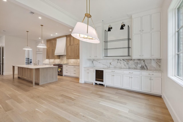 1801 Loving Ave, Dallas, TX 75214 - kitchen featuring stainless steel stove, wall chimney range hood, beverage cooler, backsplash, and light wood-style flooring