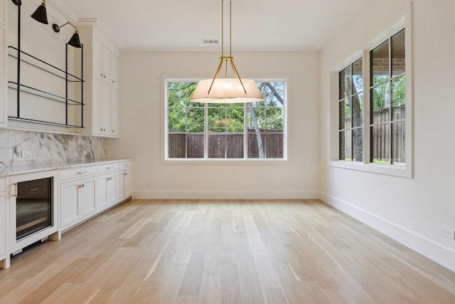 1801 Loving Ave, Dallas, TX 75214 - unfurnished dining area with wine cooler, light wood-type flooring, baseboards, and crown molding
