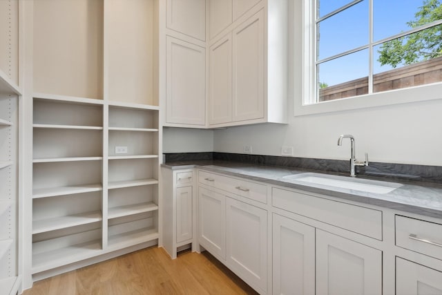 1801 Loving Ave, Dallas, TX 75214 - kitchen featuring a sink, light wood-type flooring, dark stone countertops, and white cabinets