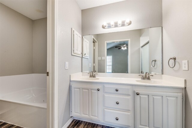 6704 Wesson Dr, Plano, TX 75023 - bathroom featuring a ceiling fan, double vanity, a garden tub, and wood finished floors