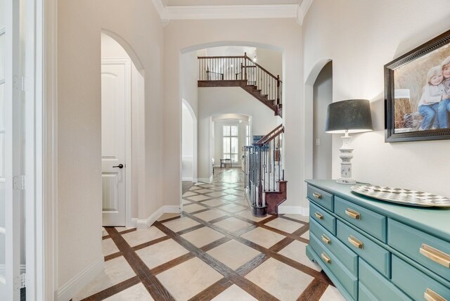 901 Jessica Ln, Prosper, TX 75078 - entrance foyer with arched walkways, inlaid floor details, stairway, baseboards, and crown molding