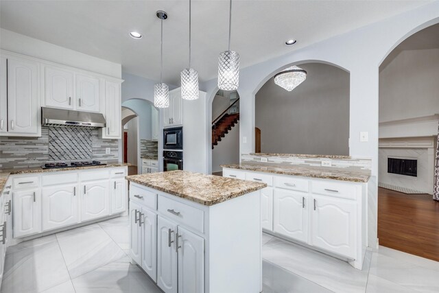 5283 W Cove Way, Grand Prairie, TX 75052 - kitchen featuring under cabinet range hood, arched walkways, black appliances, light stone countertops, and recessed lighting