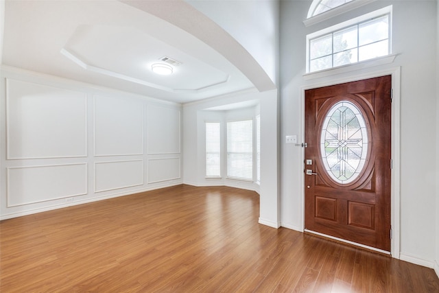 5283 W Cove Way, Grand Prairie, TX 75052 - entrance foyer featuring arched walkways, wood finished floors, a decorative wall, and a raised ceiling