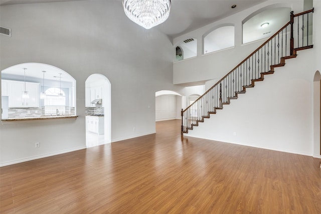 5283 W Cove Way, Grand Prairie, TX 75052 - unfurnished living room featuring wood finished floors, a high ceiling, arched walkways, a chandelier, and stairway