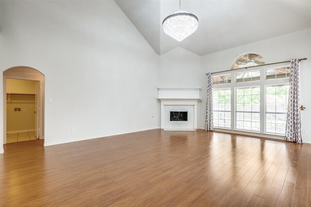 5283 W Cove Way, Grand Prairie, TX 75052 - unfurnished living room with high vaulted ceiling, arched walkways, a chandelier, a fireplace, and wood finished floors