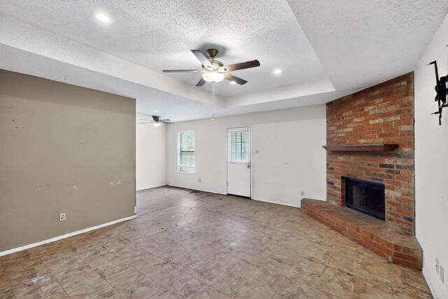 8512 Whitney Dr, White Settlement, TX 76108 - unfurnished living room featuring ceiling fan, a tray ceiling, a brick fireplace, a textured ceiling, and baseboards