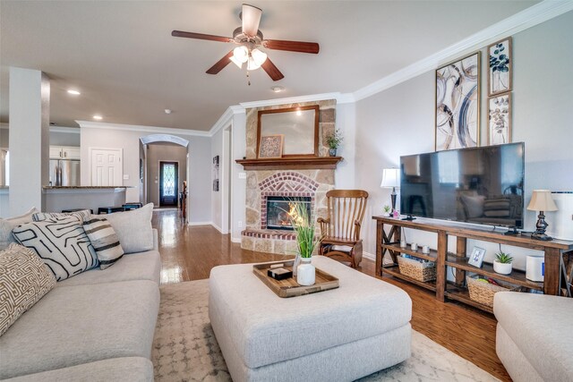 105 Cassandra Dr, Forney, TX 75126 - living room featuring crown molding, a ceiling fan, arched walkways, wood finished floors, and a fireplace
