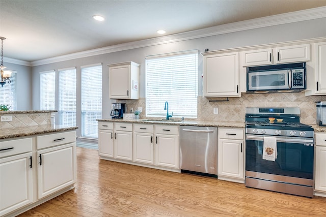 105 Cassandra Dr, Forney, TX 75126 - kitchen with stainless steel appliances, a sink, light wood-style floors, ornamental molding, and white cabinetry