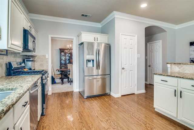 105 Cassandra Dr, Forney, TX 75126 - kitchen featuring appliances with stainless steel finishes, arched walkways, light wood-style floors, white cabinets, and crown molding