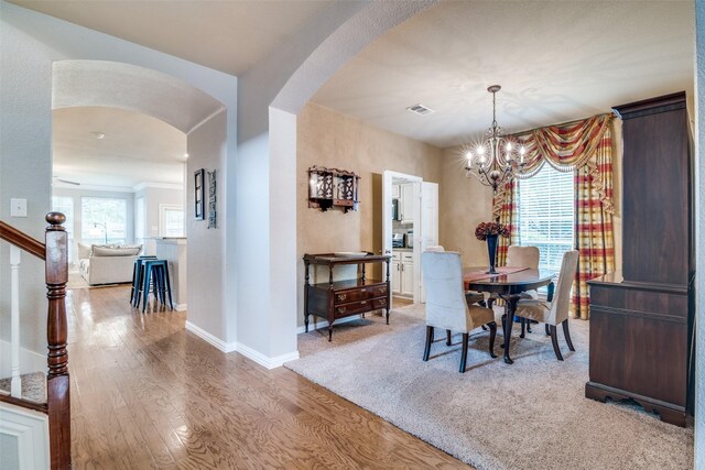 105 Cassandra Dr, Forney, TX 75126 - dining area with arched walkways, light wood-style floors, a chandelier, baseboards, and stairs