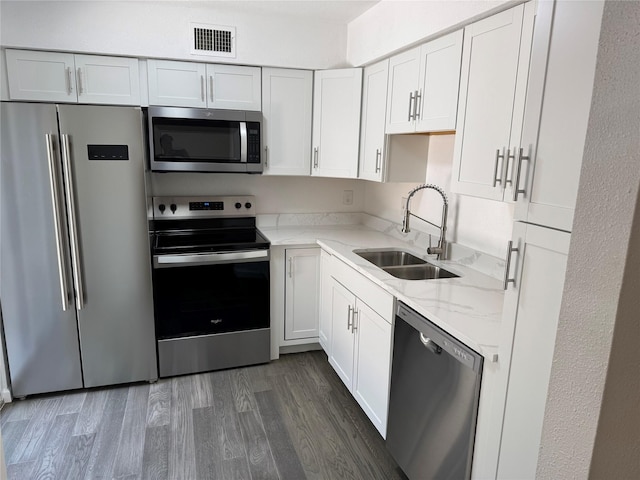 14800 Enterprise Dr Unit 17B, Farmers Branch, TX 75234 - kitchen featuring stainless steel appliances, a sink, light stone counters, dark wood-style floors, and white cabinets