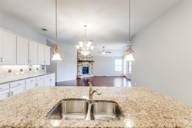 9728 Bitterroot Dr, Little Elm, TX 75068 - kitchen featuring dark wood-style flooring, light stone countertops, a fireplace, white cabinets, and pendant lighting