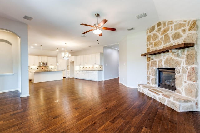 9728 Bitterroot Dr, Little Elm, TX 75068 - unfurnished living room featuring a ceiling fan, a stone fireplace, dark wood-style floors, and a chandelier