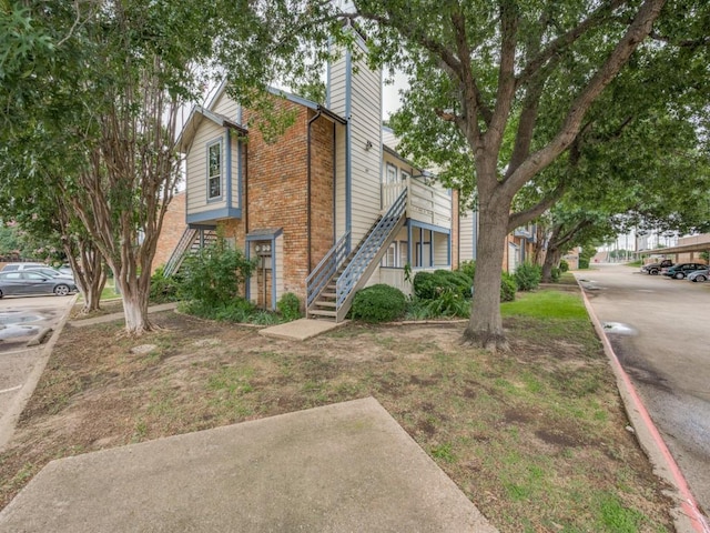 1603 Marsh Ln Unit 308, Carrollton, TX 75006 - view of side of home featuring stairway, brick siding, and a chimney