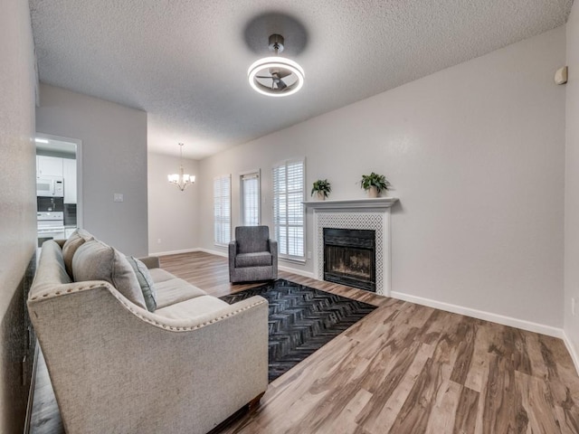 1603 Marsh Ln Unit 308, Carrollton, TX 75006 - living area with a textured ceiling, wood finished floors, a tile fireplace, a chandelier, and baseboards
