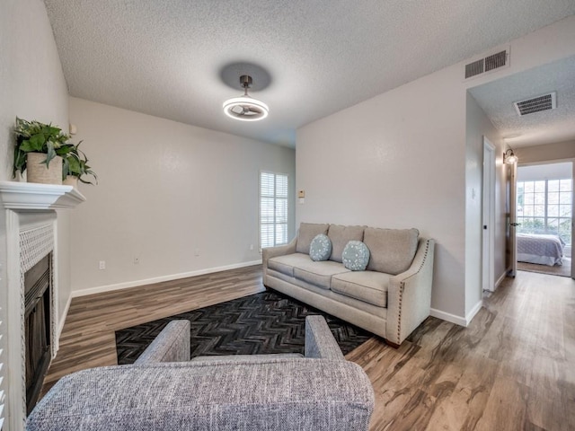 1603 Marsh Ln Unit 308, Carrollton, TX 75006 - living room with wood finished floors, a textured ceiling, baseboards, and a fireplace