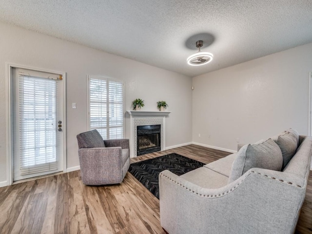 1603 Marsh Ln Unit 308, Carrollton, TX 75006 - living area with wood finished floors, a textured ceiling, a tiled fireplace, and baseboards