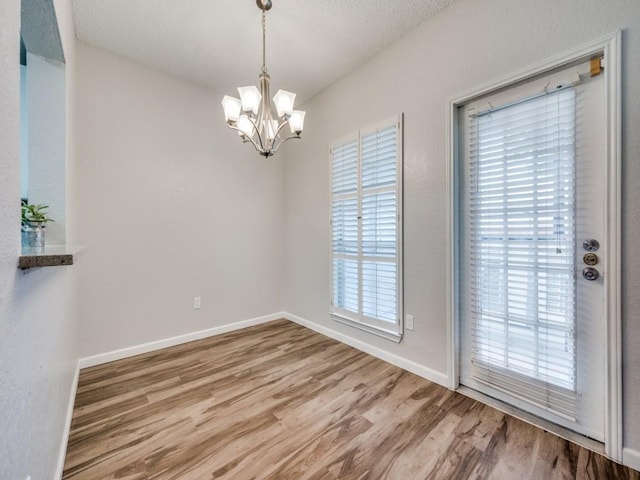 1603 Marsh Ln Unit 308, Carrollton, TX 75006 - empty room with a chandelier, wood finished floors, and baseboards