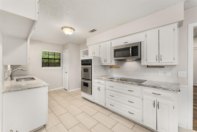 5008 Hatherly Dr, Plano, TX 75023 - kitchen featuring appliances with stainless steel finishes, a sink, decorative backsplash, a textured ceiling, and white cabinets