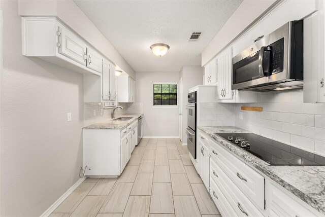 5008 Hatherly Dr, Plano, TX 75023 - kitchen featuring appliances with stainless steel finishes, a sink, baseboards, white cabinetry, and tasteful backsplash