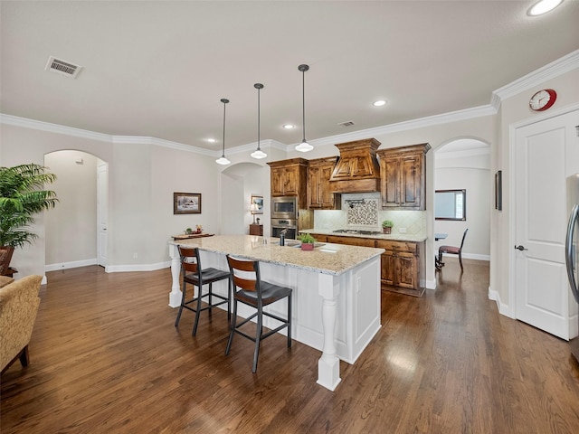 6420 Rosemary Ct, Mckinney, TX 75071 - kitchen featuring arched walkways, appliances with stainless steel finishes, custom exhaust hood, recessed lighting, and light stone countertops