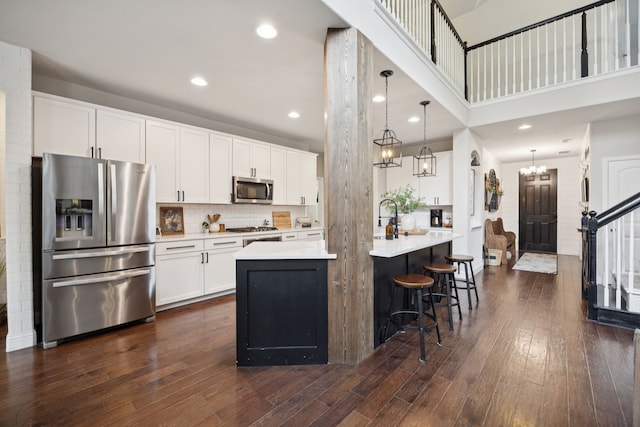 7717 Lake Worth Cv, Mckinney, TX 75071 - kitchen featuring appliances with stainless steel finishes, light countertops, dark wood-style flooring, white cabinets, and a center island with sink