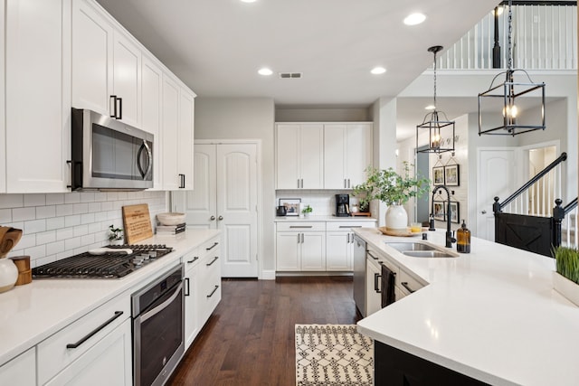 7717 Lake Worth Cv, Mckinney, TX 75071 - kitchen with stainless steel appliances, a sink, light countertops, dark wood-style floors, and white cabinetry
