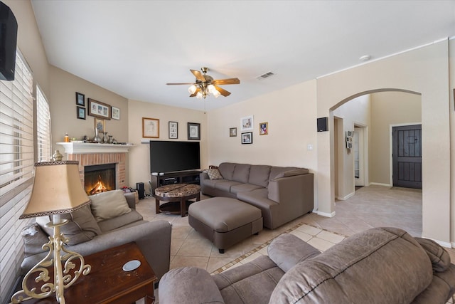 1230 Donegal Ln, Garland, TX 75044 - living room featuring arched walkways, light tile patterned floors, a ceiling fan, and a brick fireplace