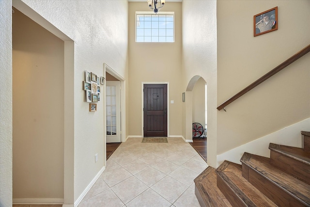 1230 Donegal Ln, Garland, TX 75044 - foyer with arched walkways, light tile patterned floors, stairs, a towering ceiling, and baseboards