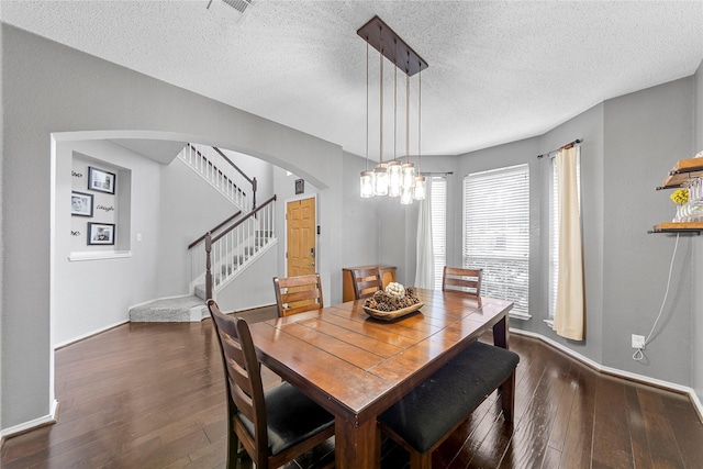 5904 Meadowcrest Ln, Sachse, TX 75048 - dining room with arched walkways, dark wood finished floors, a textured ceiling, stairway, and a chandelier