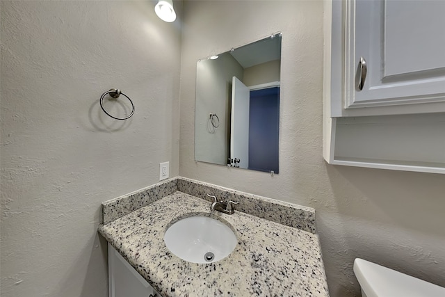 4804 Jennings Cir, The Colony, TX 75056 - half bathroom featuring vanity, toilet, and a textured wall