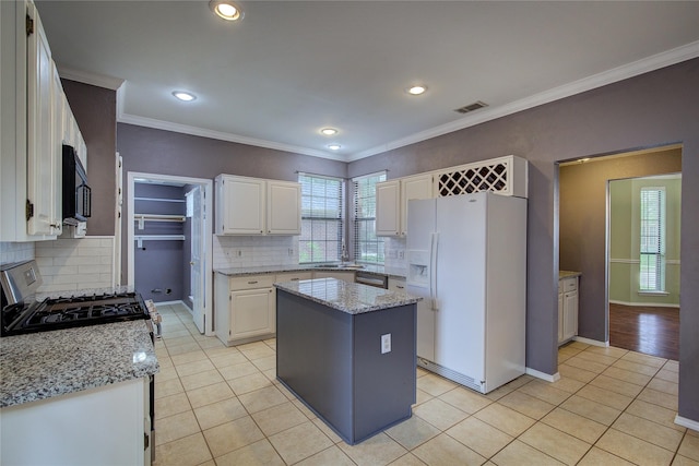 6613 Springmeadow Ln, Rowlett, TX 75089 - kitchen featuring appliances with stainless steel finishes, light tile patterned floors, white cabinetry, tasteful backsplash, and ornamental molding