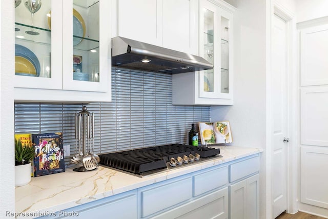 1624 Palo Duro Way, Celina, TX 75009 - kitchen featuring under cabinet range hood, stainless steel gas stovetop, white cabinetry, backsplash, and glass insert cabinets