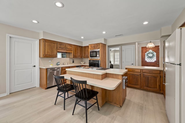 7213 Maranatha Ct, Colleyville, TX 76034 - kitchen with stainless steel appliances, a sink, light countertops, a kitchen island, and brown cabinetry