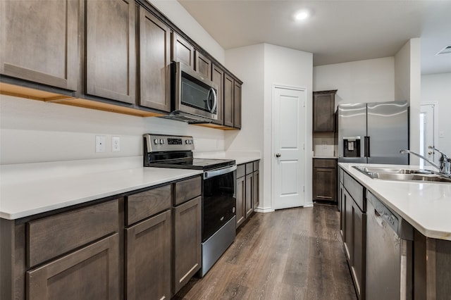 1937 Duskwood Dr, Lancaster, TX 75146 - kitchen with appliances with stainless steel finishes, dark wood-style flooring, dark brown cabinets, light countertops, and an island with sink