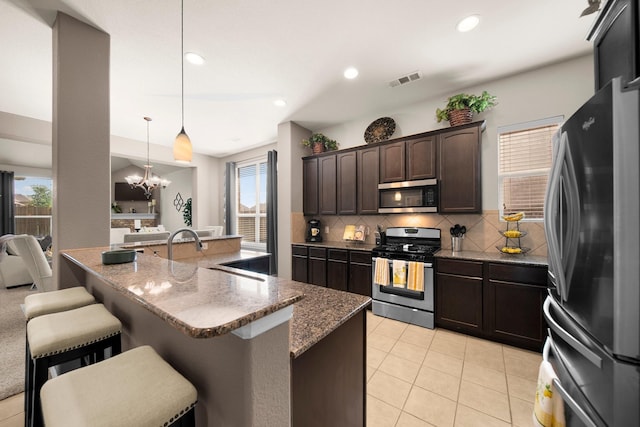 334 Hawthorn Dr, Fate, TX 75087 - kitchen featuring appliances with stainless steel finishes, decorative backsplash, a kitchen bar, plenty of natural light, and recessed lighting