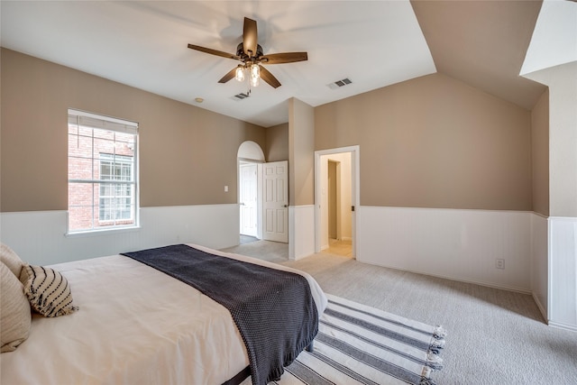 8250 Library St, Frisco, TX 75034 - bedroom with wainscoting, light colored carpet, arched walkways, vaulted ceiling, and a ceiling fan