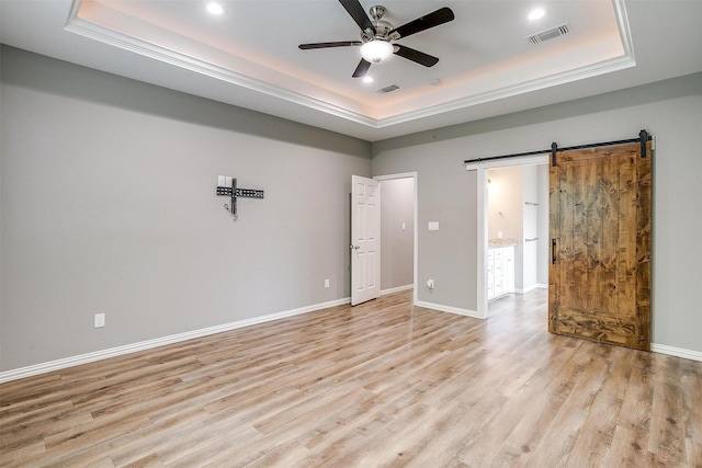 430 Mitchell Blvd, Weatherford, TX 76087 - empty room with a tray ceiling, ceiling fan, light wood finished floors, a barn door, and recessed lighting